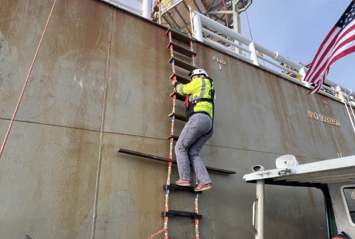 Worker ascending ship ladder